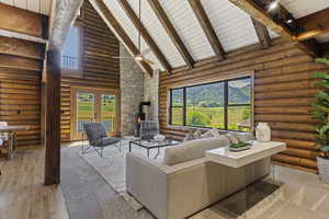 Living room featuring rustic walls, a wood stove, a high wood beamed ceiling, french doors, and wood finished floors