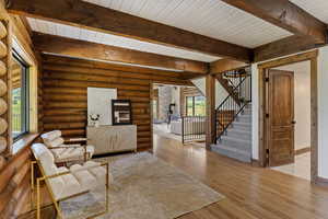 Living room featuring wood finished floors, rustic walls, and a wood ceiling with exposed beams