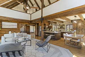 Living area with light wood-style floors, ceiling fan, rustic walls, and lofted ceiling