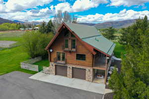 View of front facade featuring log siding, stone siding, a mountain view, and a garage
