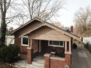 View of front facade with a gate, a chimney, brick siding, and covered porch
