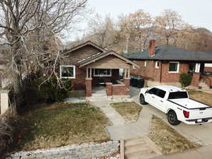 View of front of property featuring brick siding, a porch, and a chimney