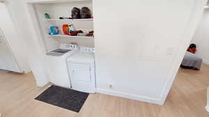Laundry area featuring light wood-style floors, separate washer and dryer, and electric panel