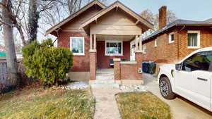 View of front facade featuring brick siding and a chimney