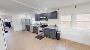 Kitchen featuring stainless steel appliances, light wood finished floors, light stone countertops, and recessed lighting