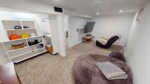 Living area with light colored carpet and recessed lighting