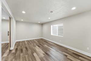 Below grade area with a textured ceiling, recessed lighting, and light wood-style floors