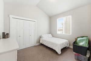 Carpeted bedroom featuring a closet and vaulted ceiling