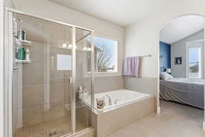 Full bath with ensuite bathroom, a stall shower, a bath, tile patterned floors, and lofted ceiling