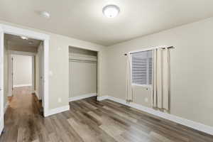 Unfurnished bedroom featuring wood finished floors, a closet, and a textured ceiling
