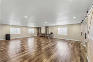 Unfurnished living room with a barn door, light wood-type flooring, recessed lighting, and healthy amount of natural light