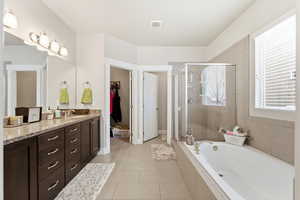 Full bath with a stall shower, vanity, a bath, a walk in closet, and light tile patterned flooring