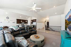 Living area with a ceiling fan, lofted ceiling, light colored carpet, and wainscoting