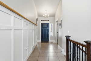 Entrance foyer with light tile patterned flooring and hanging lights