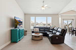 Living area with lofted ceiling, ceiling fan, and light carpet
