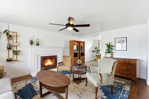 Living area featuring wood finished floors, ceiling fan, and a fireplace