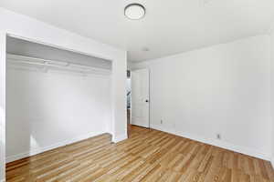 Unfurnished bedroom with wood finished floors and a closet