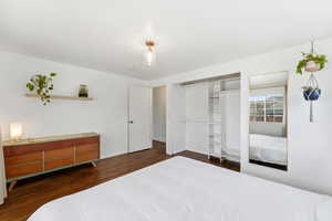 Bedroom with dark wood-style flooring and a closet