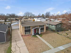 View of front of home featuring a residential view, brick siding, a shingled roof, and driveway