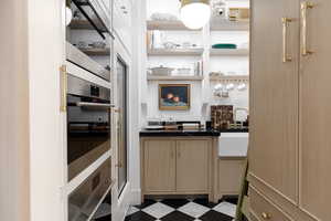 Bar area with dark floors, light wood finish cabinetry, and open shelves