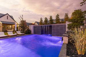 Pool at dusk featuring a fenced backyard and a patio