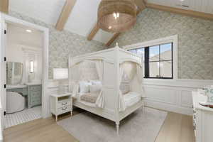 Bedroom with wallpapered walls, light wood-style flooring, wainscoting, and a wooden ceiling with exposed beams