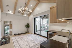 Kitchen featuring wine cooler, light wood finished floors, hanging lights, plenty of natural light, and lofted ceiling