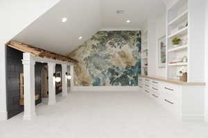 Unfurnished living room featuring lofted ceiling, light colored carpet, recessed lighting, built in features, and wallpapered walls