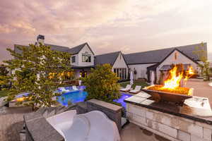 Pool at dusk featuring an outdoor fire pit, a patio area, and an outdoor pool