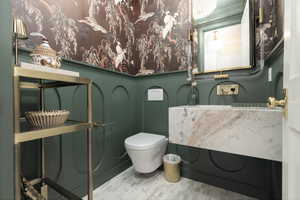 Half bathroom with vanity and wallpapered walls