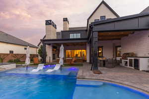 Back of property with an outdoor kitchen / dining area, a patio, wine cooler, and a chimney