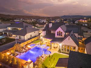 Back of property at dusk with a patio, a fenced backyard, a pool with connected hot tub, and a residential view