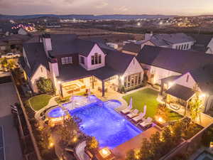 Pool at dusk with a patio area, a pool with connected hot tub, an outdoor living space with a fire pit, a fenced backyard, and a residential view