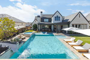 Back of property with a patio area, a chimney, a fenced backyard, and a pool with connected hot tub