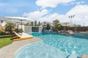 Combined pool / hot tub with a patio area and a fenced backyard