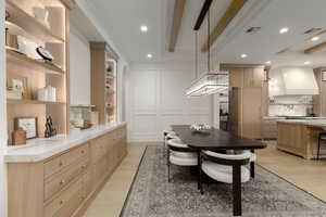 Dining area featuring a decorative wall, built in shelves, light wood-style flooring, recessed lighting, and ornamental molding