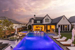 Rear view of property featuring a patio, a fenced backyard, a chimney, and a pool with connected hot tub