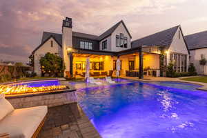 Rear view of house featuring a patio area, an outdoor living space with a fire pit, a chimney, and a pool with connected hot tub