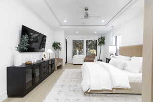 Bedroom featuring light wood-style floors, ceiling fan, a raised ceiling, recessed lighting, and ornamental molding