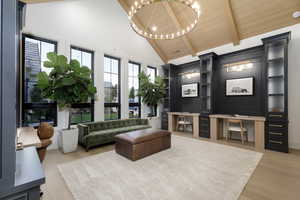 Living room with light wood-style floors, suspended lighting, built in desk, and a high wooden beamed ceiling
