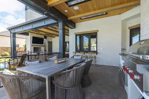 View of patio / terrace with an outdoor stone fireplace, grilling area, and outdoor dining space
