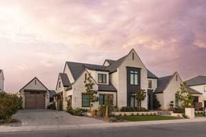View of front of home featuring stone siding, decorative driveway, and an outdoor structure