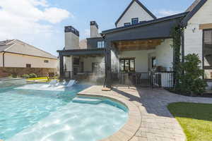 Rear view of house with a patio area, a chimney, and a pool with connected hot tub