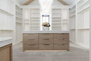 Walk in closet featuring lofted ceiling, a chandelier, and light carpet