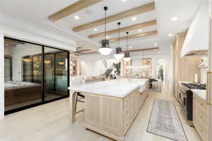 Kitchen featuring arched walkways, light wood finish cabinets, open floor plan, a raised ceiling, and a kitchen bar