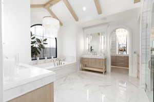 Full bathroom with two vanities, a garden tub, lofted ceiling with beams, light marble finish flooring, and a stall shower