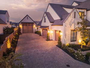 View of front of home featuring decorative driveway, stone siding, and a standing seam roof