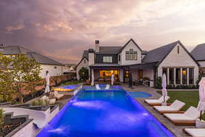 Rear view of house with a patio area, a fenced backyard, a chimney, a pool with connected hot tub, and a standing seam roof