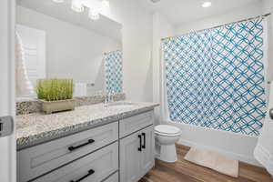Bathroom with vanity, dark wood-style flooring, shower / bath combination with curtain, and recessed lighting