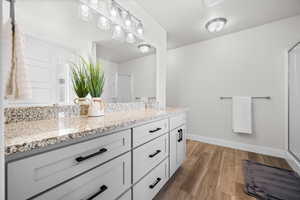 Bathroom with double vanity, a shower stall, and light wood-style flooring